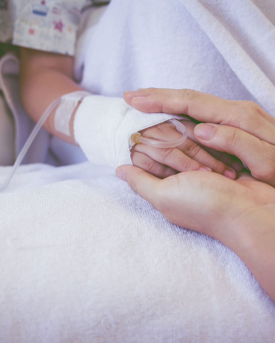 Hand hält die eines Kindes mit Infusion – einfühlsame Intensivpflege bei Aariana Pflegedienst